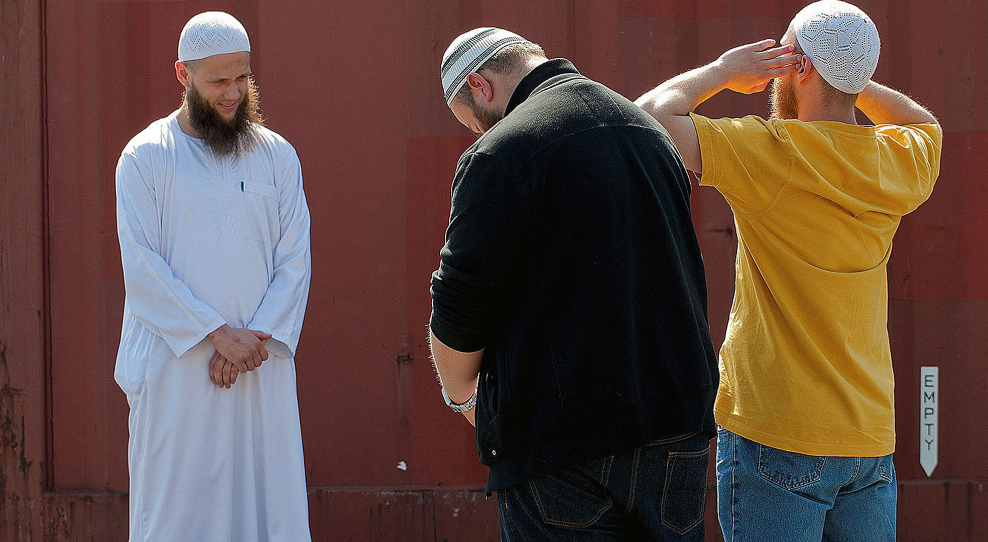 Radikální muslimský předák Sven Lau (vlevo) se modlí na parkovišti u KFC.